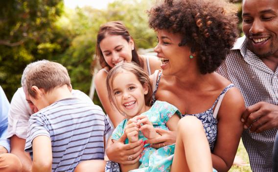 A group of family members and friends enjoying a sunny day outdoors, laughing and playing together.