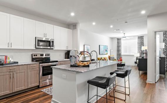 A modern kitchen with white cabinetry, stainless steel appliances, and a spacious island with barstools.