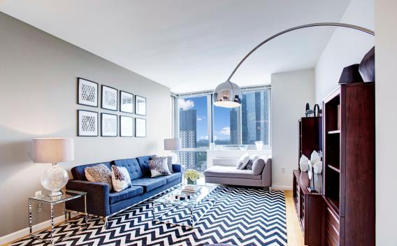 Bright and stylish living area at Skyline New Rochelle apartments, boasting floor-to-ceiling windows, chic décor, and expansive cityscape views.