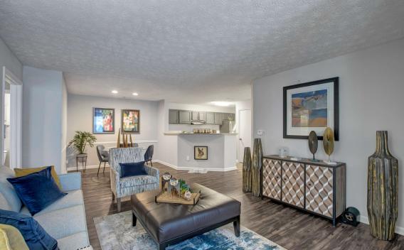 Stylish and open-concept living and dining area featuring modern décor, wood-style flooring, and a view into the sleek, updated kitchen with stainless steel appliances.