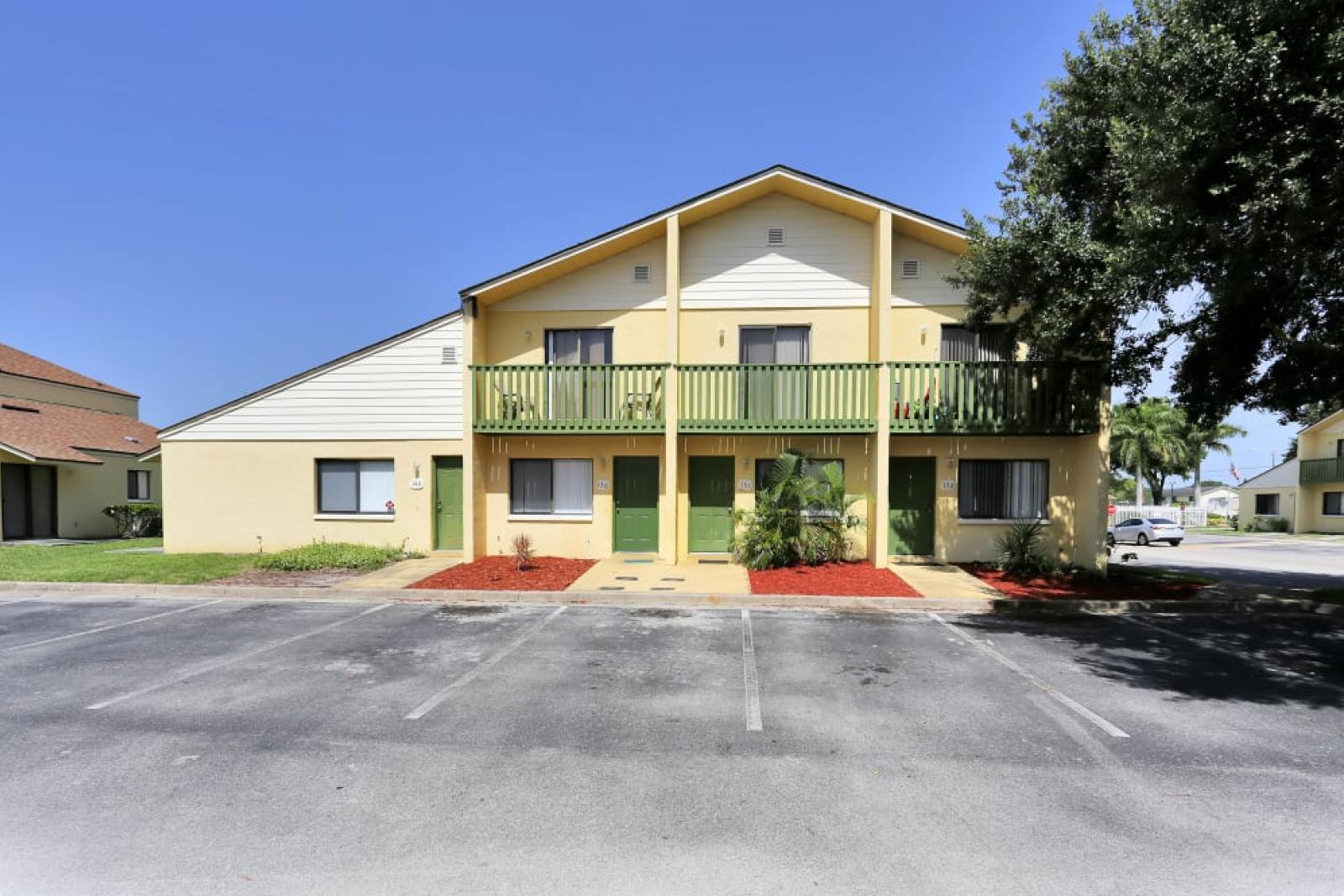 Exterior of Townhome Building: A vibrant yellow townhome building with green doors, small balconies, and neatly landscaped surroundings.