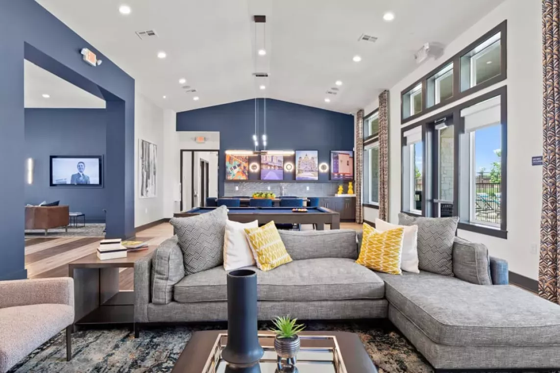 A spacious clubhouse with a contemporary sectional sofa, vibrant decor, and pool table, designed for social gatherings and relaxation.