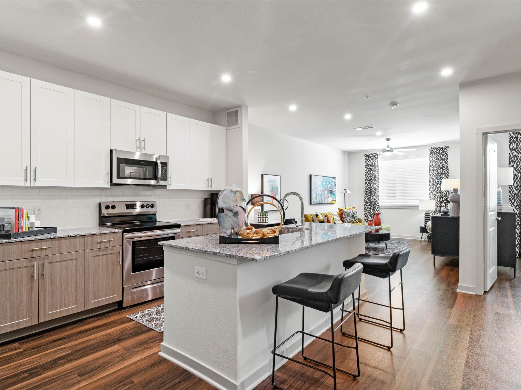 A modern kitchen with white cabinetry, stainless steel appliances, and a spacious island with barstools.