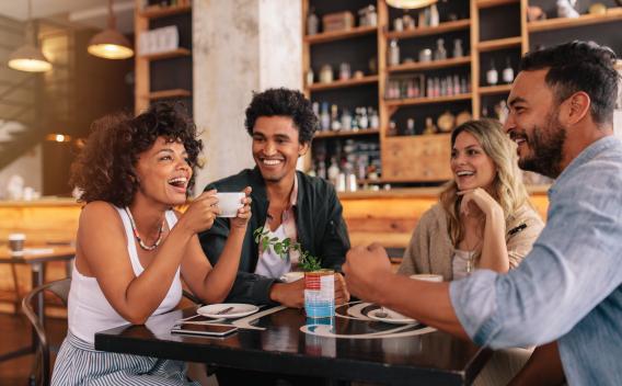 "Group of friends laughing and enjoying coffee together in a cozy cafe."