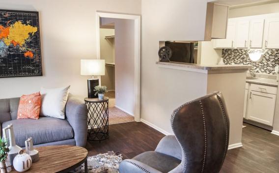 Cozy studio apartment featuring a comfortable bed with decorative pillows, a small dining area, and an efficient kitchen, with vibrant artwork adding a personal touch to the living space.