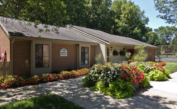 Exterior view of the North River Place Apartments rental office surrounded by vibrant landscaping and lush greenery, showcasing a welcoming atmosphere