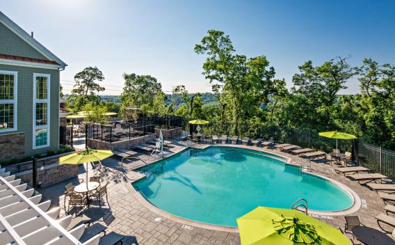 A spacious outdoor pool area with lounge chairs and shaded seating, offering stunning views of lush greenery, ideal for relaxation and leisure.
