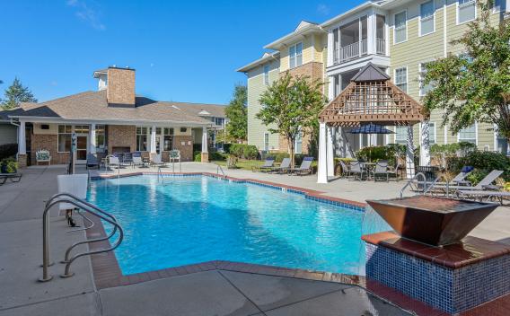 A sparkling outdoor pool with a water feature, surrounded by lounge chairs and a charming gazebo for shaded seating.