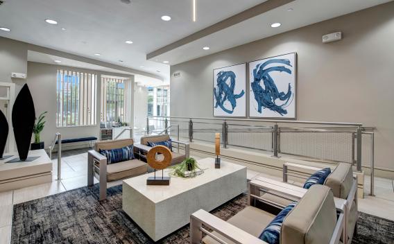A modern seating area with sleek furniture, a large coffee table, and abstract blue artwork on the wall.