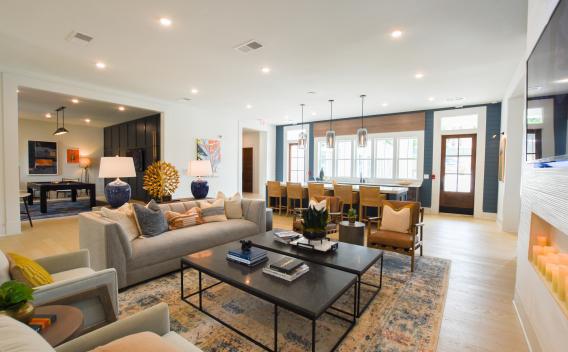 A beautifully designed resident lounge with contemporary furnishings, a cozy seating area, a fireplace, and a stylish bar with pendant lighting, creating an inviting and upscale community space.