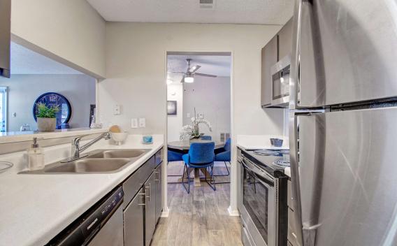 Bright, contemporary kitchen with sleek granite-style countertops, modern appliances, and white cabinetry. The space is well-lit with recessed lighting and natural light from a nearby window, creating a fresh and inviting atmosphere perfect for cooking and entertaining.