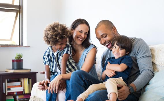 Two parents in a living room on a couch with two children on their laps