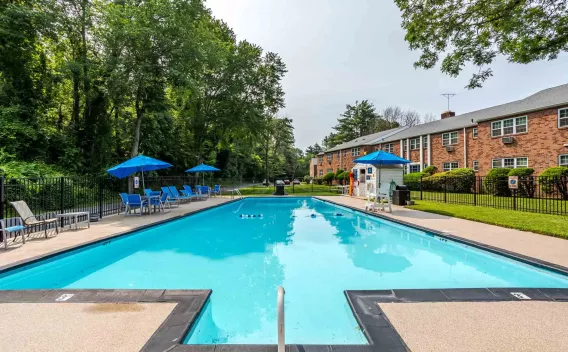 Expansive resort-style pool with plenty of seating and umbrellas for residents to enjoy at Scudder Falls.