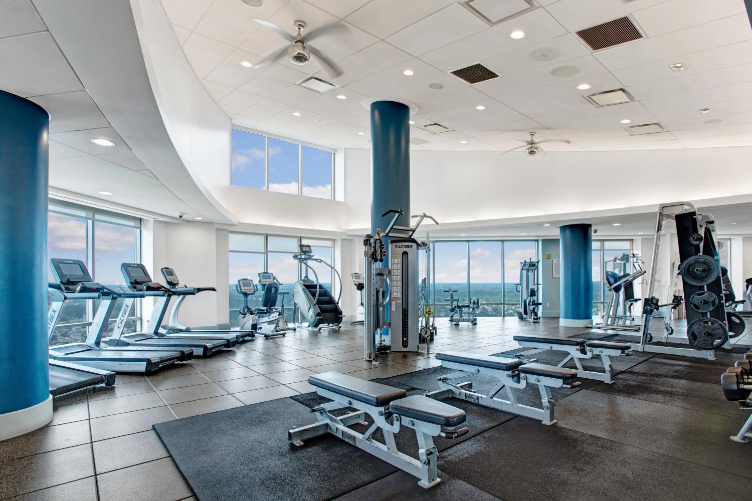 A state-of-the-art fitness center with cardio machines, strength training equipment, and floor-to-ceiling windows showcasing stunning skyline views, enhancing your workout experience.