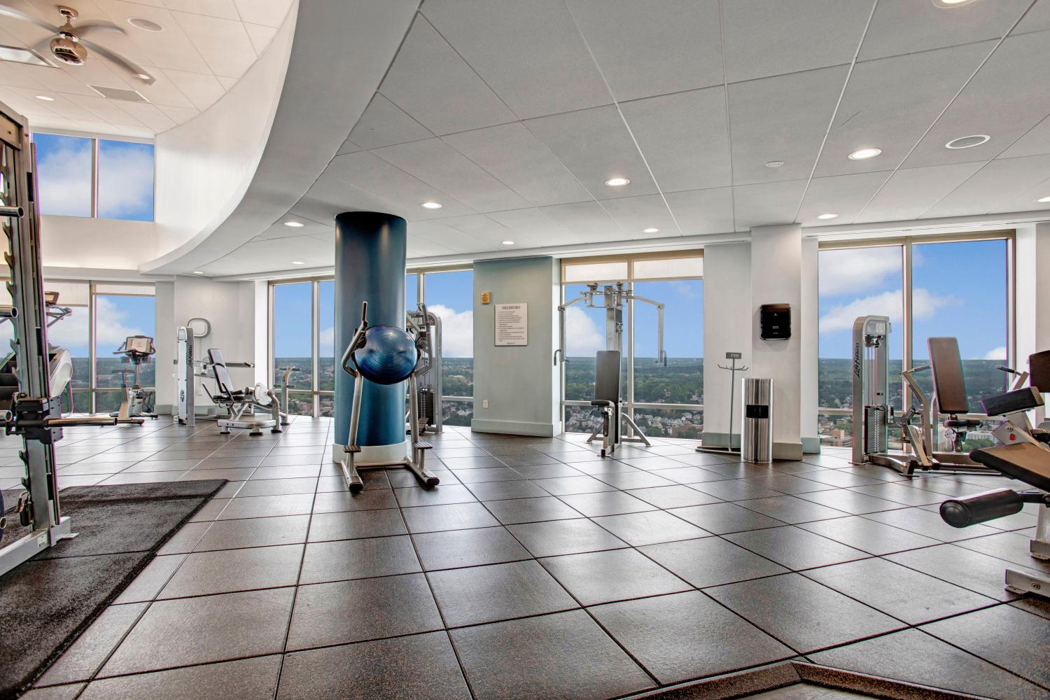 A state-of-the-art fitness center with cardio machines, strength training equipment, and floor-to-ceiling windows showcasing stunning skyline views, enhancing your workout experience.
