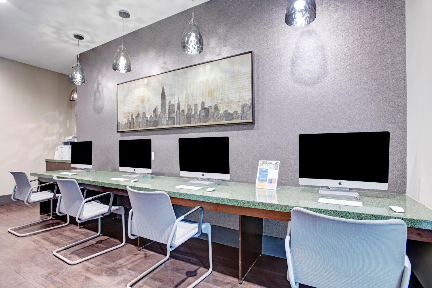 State-of-the-art business center with a row of iMac computers, ergonomic chairs, and modern lighting fixtures.