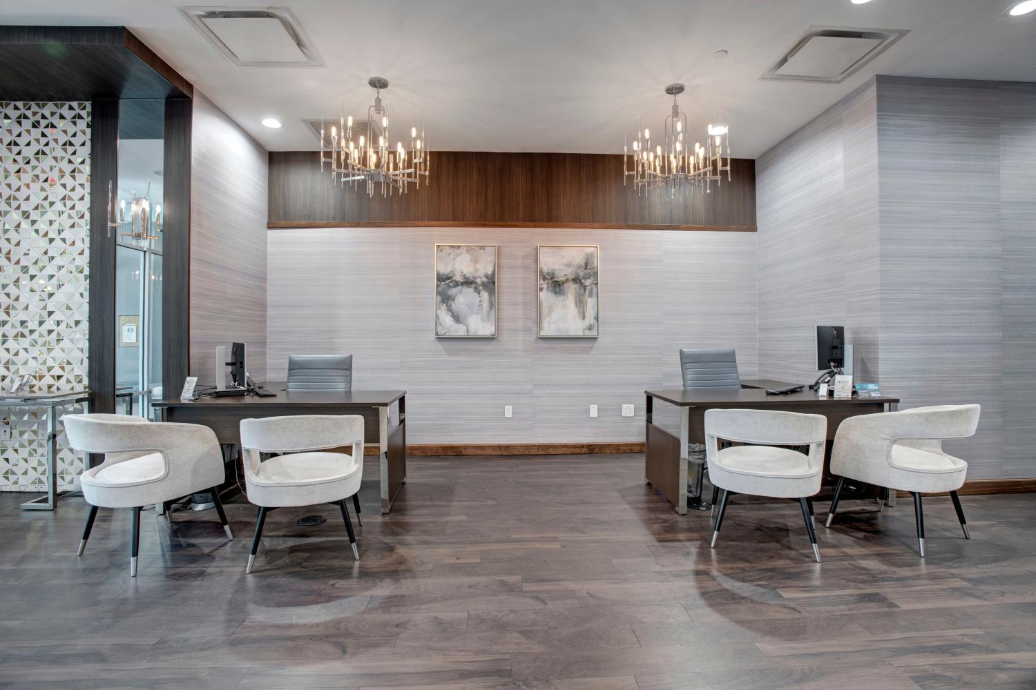 The modern leasing office at Skyline New Rochelle, featuring chic chandeliers, sleek workstations, and comfortable seating.