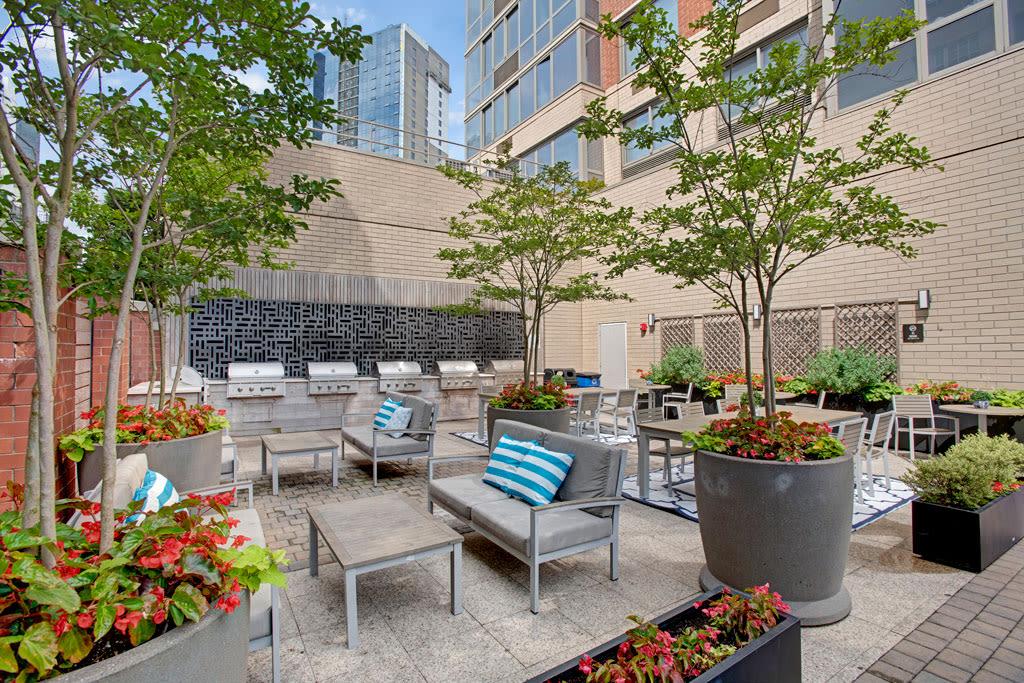 An outdoor grilling and dining space with stainless steel grills, tables, and vibrant greenery for social gatherings.