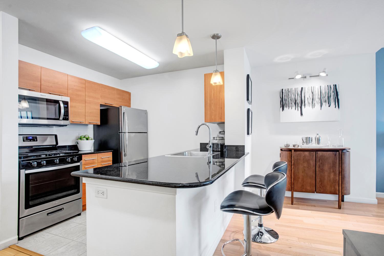 A sleek kitchen with stainless steel appliances, wooden cabinetry, and a spacious island counter perfect for meal preparation or casual dining.