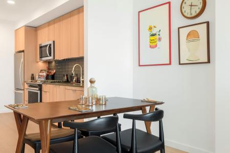 Spacious dining area adjoining a modern kitchen, featuring stylish artwork and sophisticated decor.