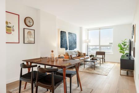 Open-concept dining and living area with stylish furnishings, large windows, and natural light.