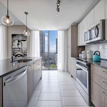 Stylish kitchen with custom cabinetry, quartz countertops, and a scenic view through floor-to-ceiling windows in Parkline Miami apartments.