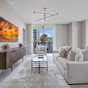 Chic living room with cozy seating, a stunning cityscape view, and a modern chandelier in Parkline Miami luxury apartments.