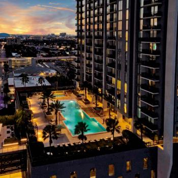 An illuminated pool deck at night at Parkline Miami Luxury Apartments, with lounge chairs and palm trees creating a sophisticated ambiance.