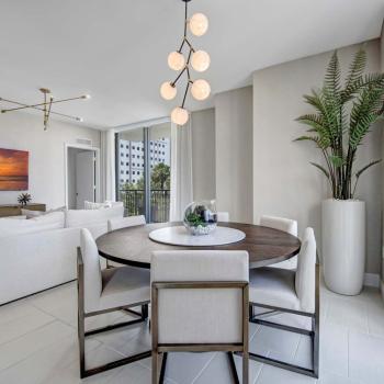 Dining area with a round table, modern light fixture, and large windows for natural light and breathtaking city views in Parkline Miami.