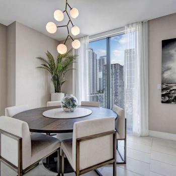 Bright dining space with contemporary decor, lush plant accents, and floor-to-ceiling windows showcasing stunning urban scenery at Parkline Miami.