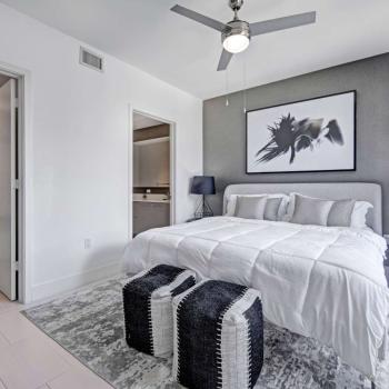 Spacious bedroom with a modern design, featuring a king-sized bed, stylish black-and-white artwork, and a ceiling fan in Parkline Miami apartments.
