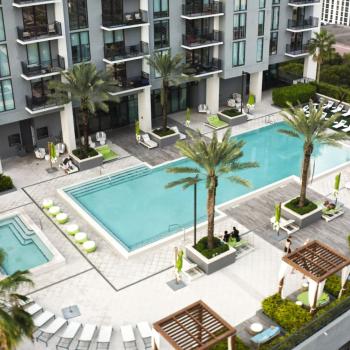 Close-up of Parkline Miami's rooftop pool area with palm trees, shaded cabanas, and ample lounging space for relaxation.