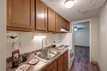 Galley-style kitchen with wood cabinets and white appliances at Apple Ridge.