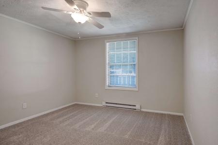 Bedroom with ceiling fan and neutral carpeting at Apple Ridge.
