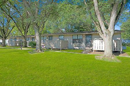 Exterior view of Apple Ridge apartments with shaded walkways and mature trees.