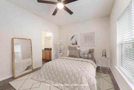 Virtually staged bedroom at Grandview at Lake Murray with a plush bed, ceiling fan, large mirror, and modern neutral decor.
