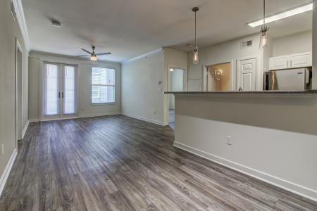 Unfurnished open living space with wood-style floors, ceiling fan, and natural light at The Saulet Apartments