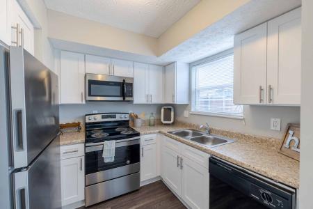 Bright kitchen with stainless steel appliances and white cabinets.