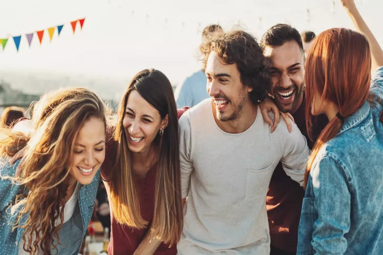 Group of friends laughing and enjoying an outdoor gathering at Wingwood Apartments, highlighting a lively and connected community atmosphere.