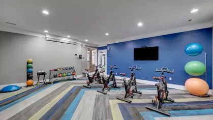 Fitness center featuring stationary bikes, colorful exercise balls, and a vibrant blue accent wall, creating a modern and energetic space for residents to stay active.