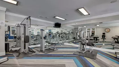 Spacious fitness center featuring a variety of strength-training machines, free weights, and bright lighting, creating a well-equipped and modern workout space for residents.