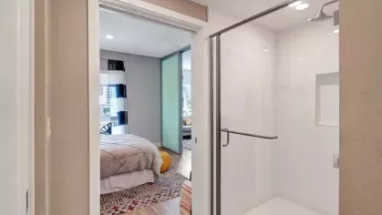 Hallway with a walk-in shower and view of the bedroom.
