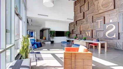 Bright and welcoming lobby with modern furniture, large typography wall art, and indoor plants.