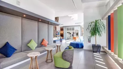 Lounge area with cushioned bench seating, colorful pillows, and small marble tables.