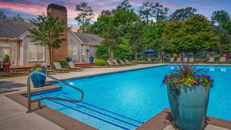 A close-up view of the sparkling pool with colorful planters and relaxing lounge areas nearby.