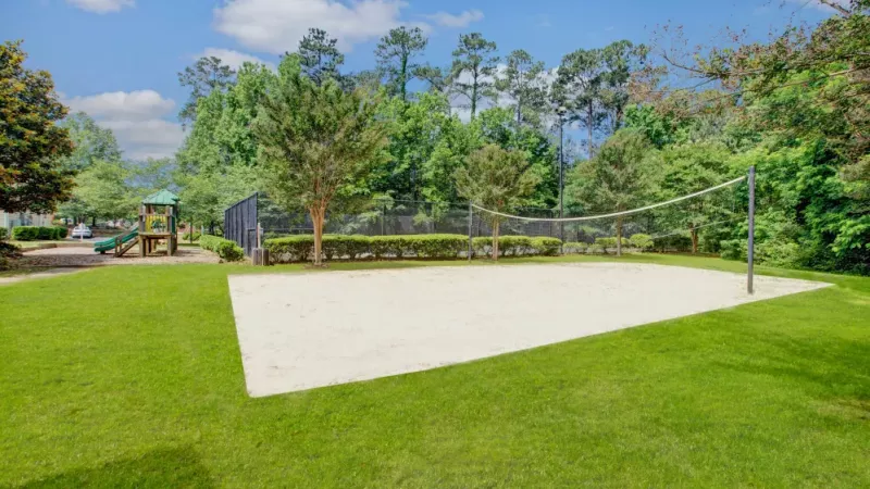 A sand volleyball court nestled among trees, providing a scenic spot for outdoor activities.