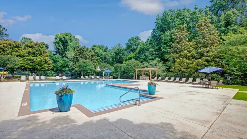 A poolside area featuring umbrellas, lounge chairs, and dining tables, offering a perfect space to unwind outdoors.