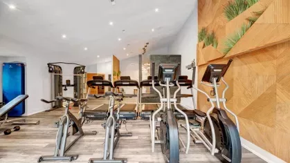 A spacious workout room with ellipticals, treadmills, and modern wood-paneled walls with greenery accents.