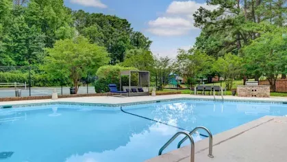 Sparkling pool with lounge chairs, greenery, and a relaxing outdoor vibe.