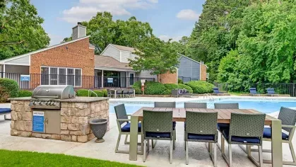 Poolside grilling station with outdoor seating and lush surroundings.